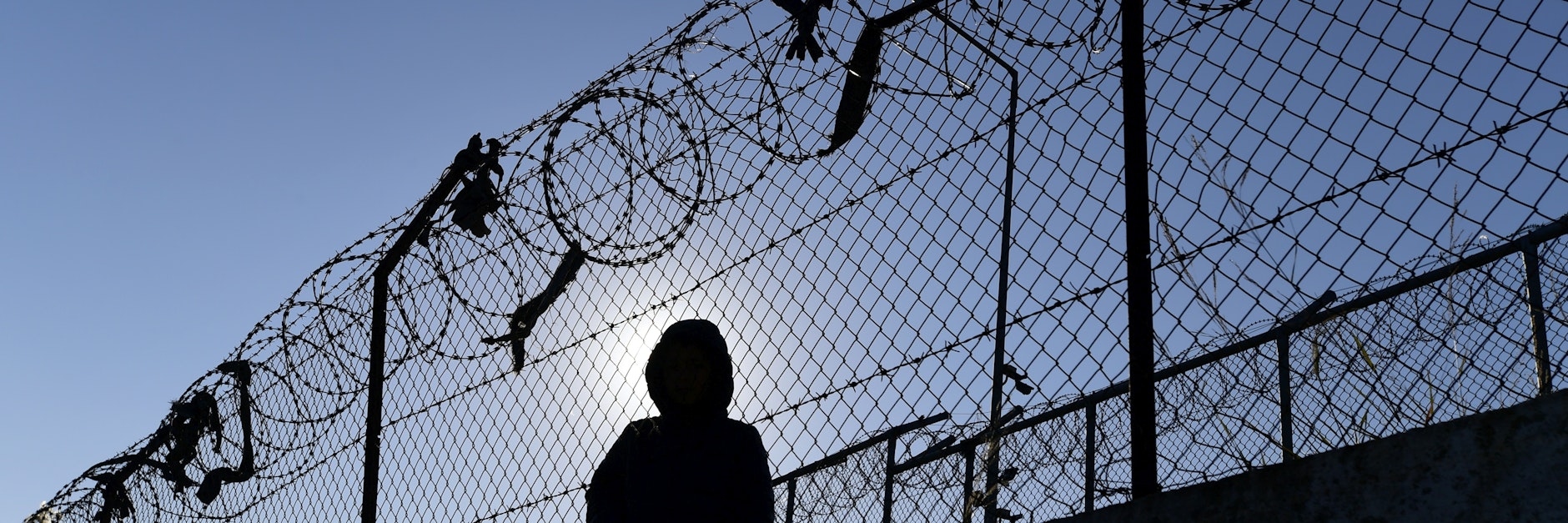 Ein Flüchtling sitzt an einem Zaun des Flüchtlingslagers Moria auf Lesbos.