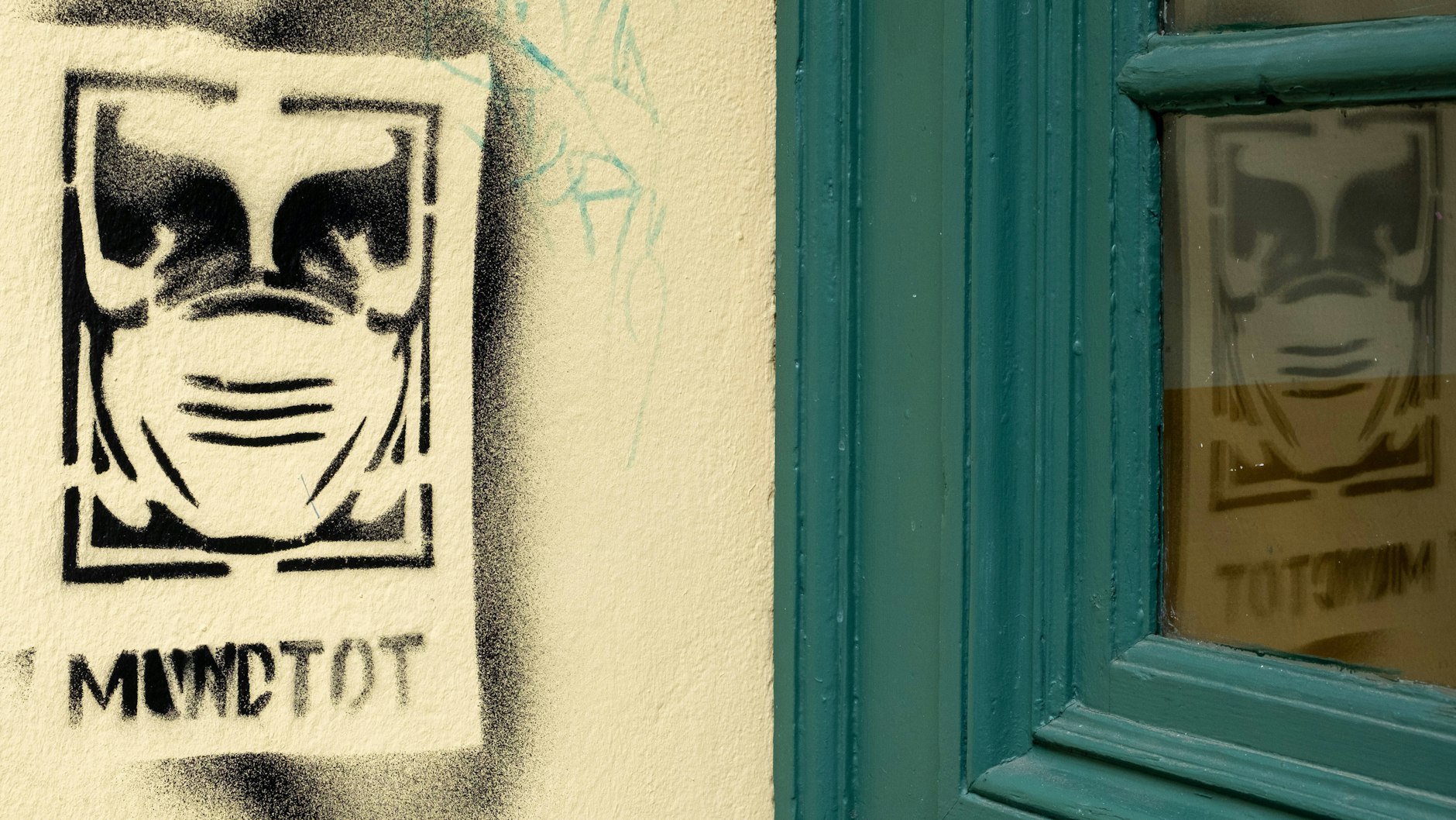 Graffito mit dem Gesicht einer Person mit einer Mund-Nasen-Maske und dem Schriftzug „Mundtot“ in Berlin-Prenzlauer Berg.