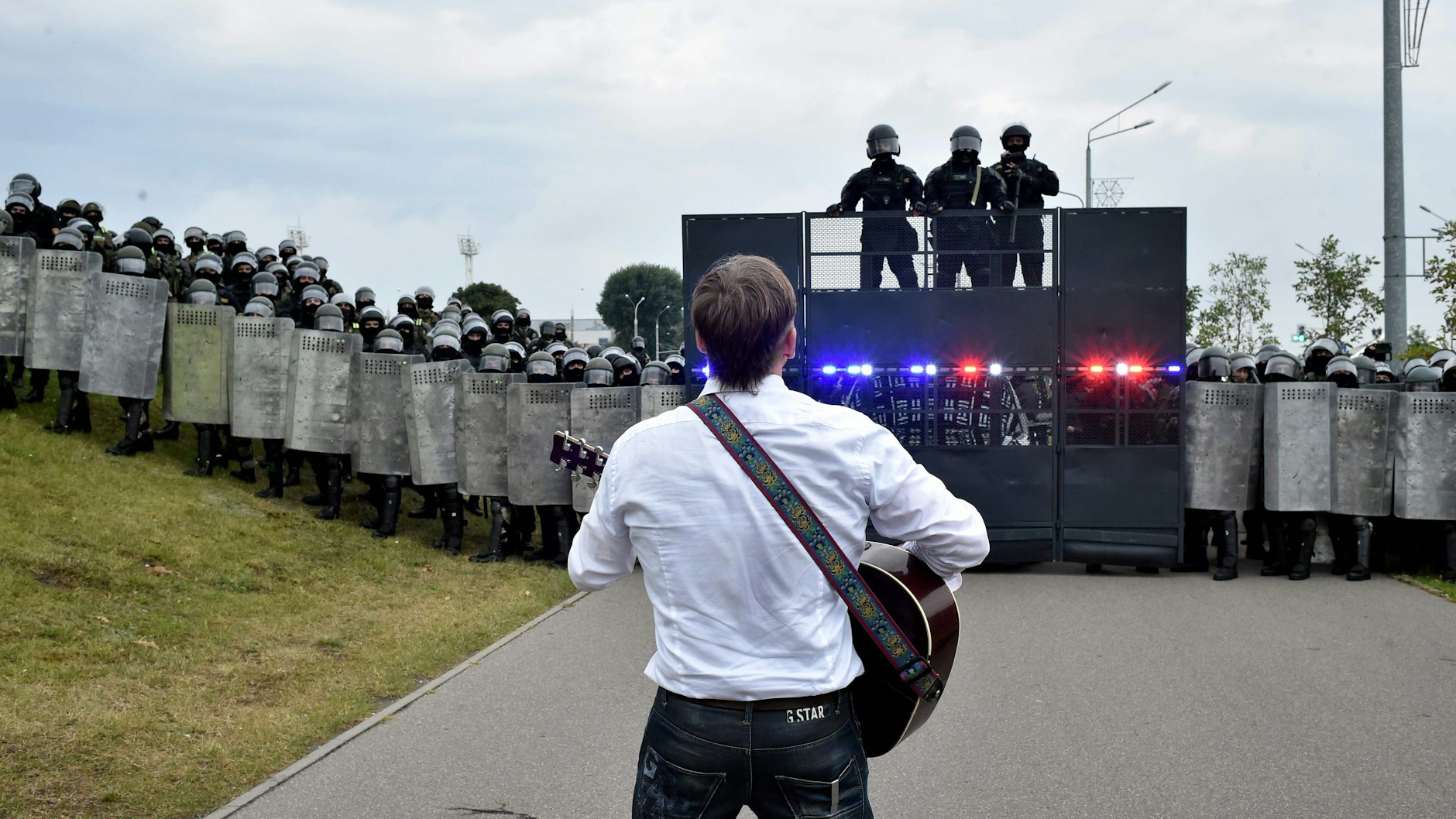 Ein Demonstrant spielt Gitarre vor einer Mauer aus hochgerüsteten Soldaten am Präsidenten-Palast. 