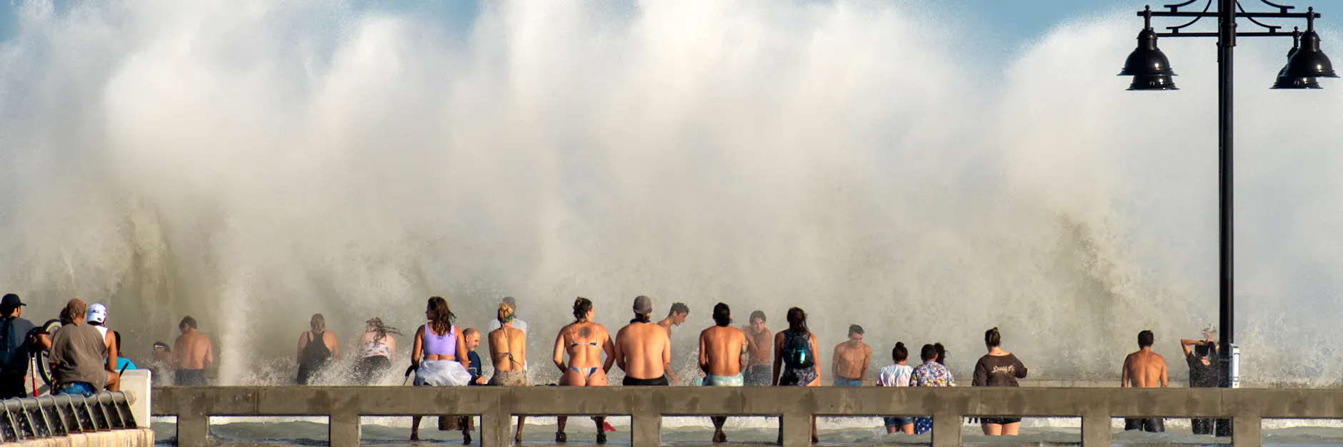 Strandbesucher in Key West stehen vor einer großen Welle, die wegen des starken Tropensturms „Laura“ zustande kommt. 