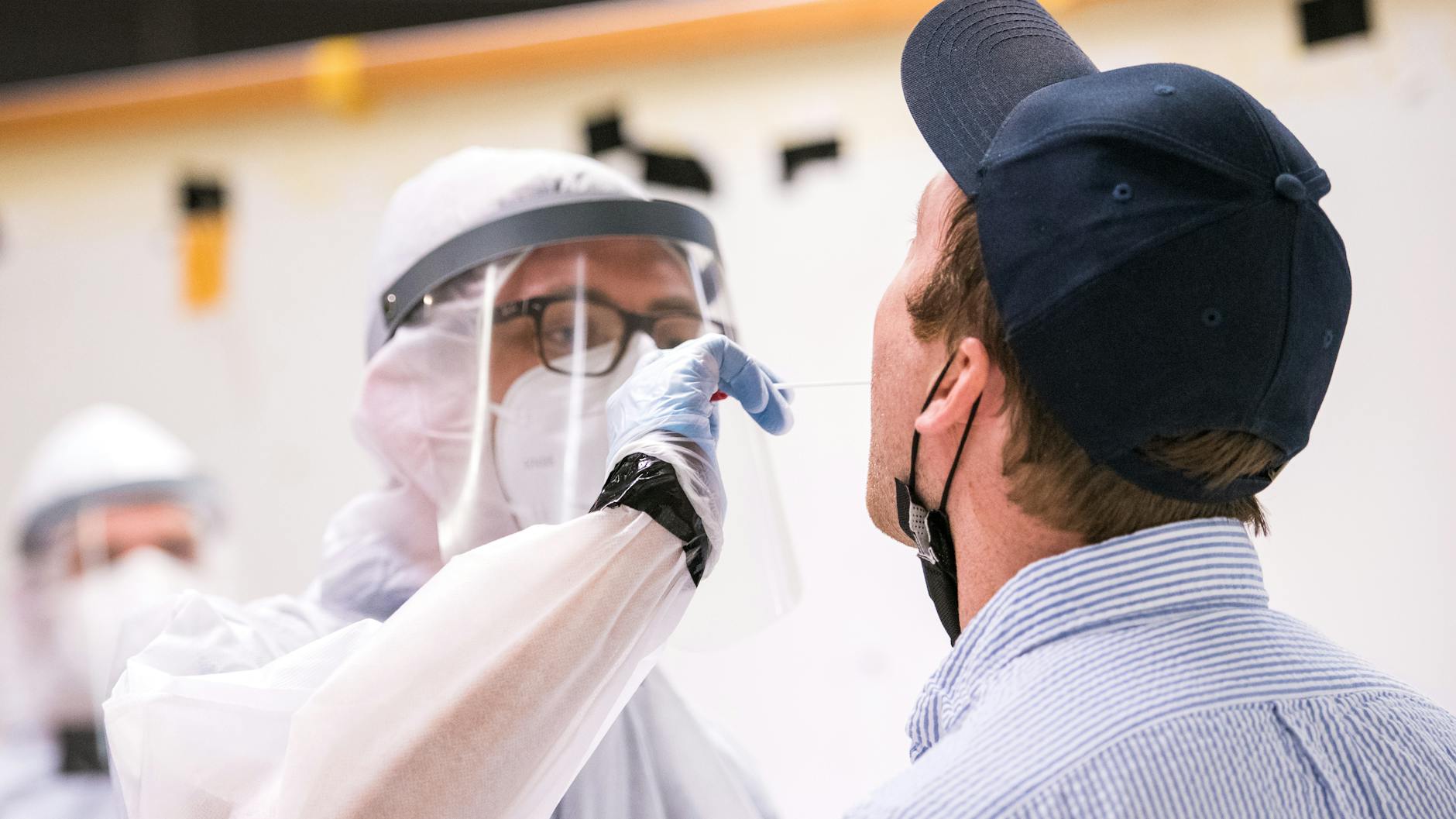 Ein Reisender (r.) lässt am Flughafen von einem Mitarbeiter des Deutschen Roten Kreuzes (DRK) einen Corona-Test machen.