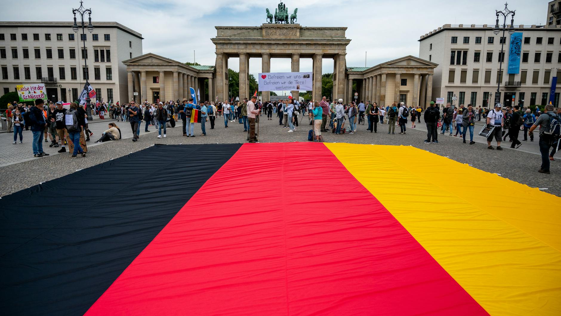 Vor dem Brandenburger Tor liegt bei dem Protest gegen die staatlichen Corona-Maßnahmen eine große Deutschlandflagge.
