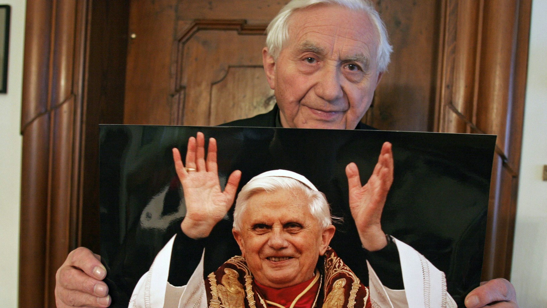 Der inzwischen verstorbene Georg Ratzinger hält ein Foto seines Bruders hoch, das ihn kurz nach der Wahl zum Papst im Jahr 2005 zeigt.