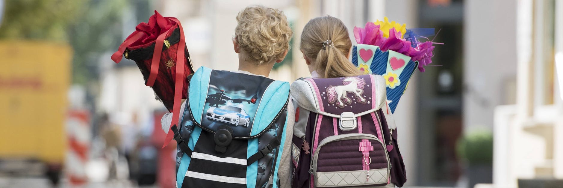 Zwei Kinder mit Schultüte auf Schulweg.