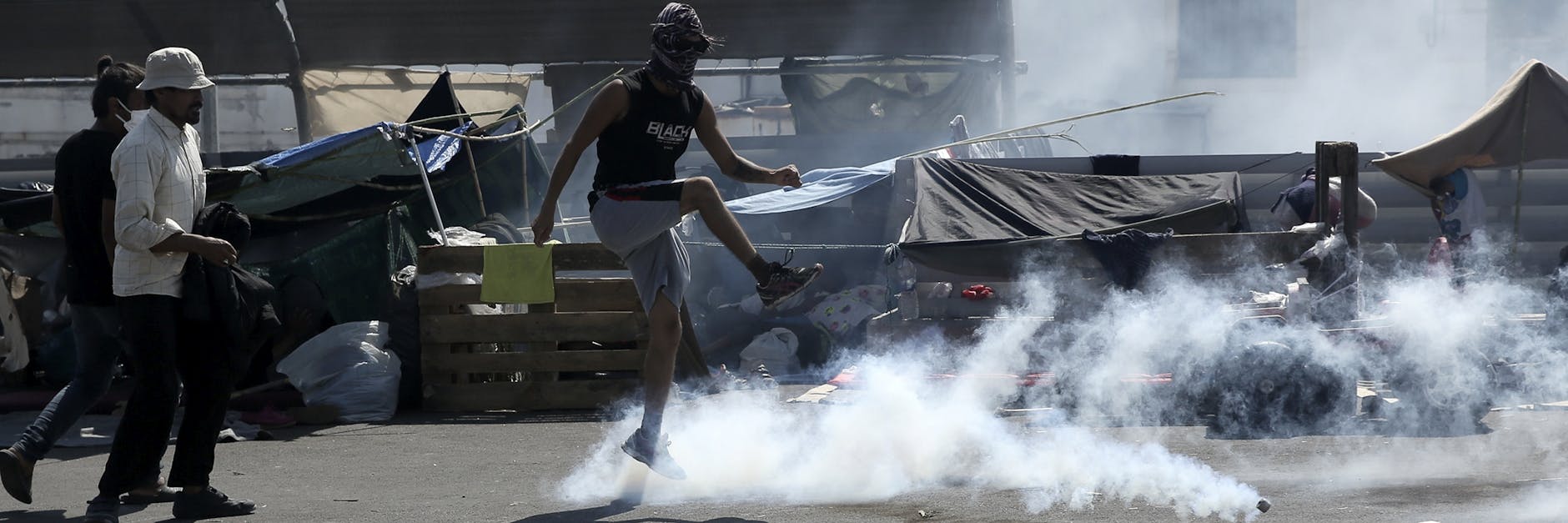 Eine Mann tritt bei Zusammenstößen zwischen Migranten und der Polizei gegen einen Tränengaskanister.