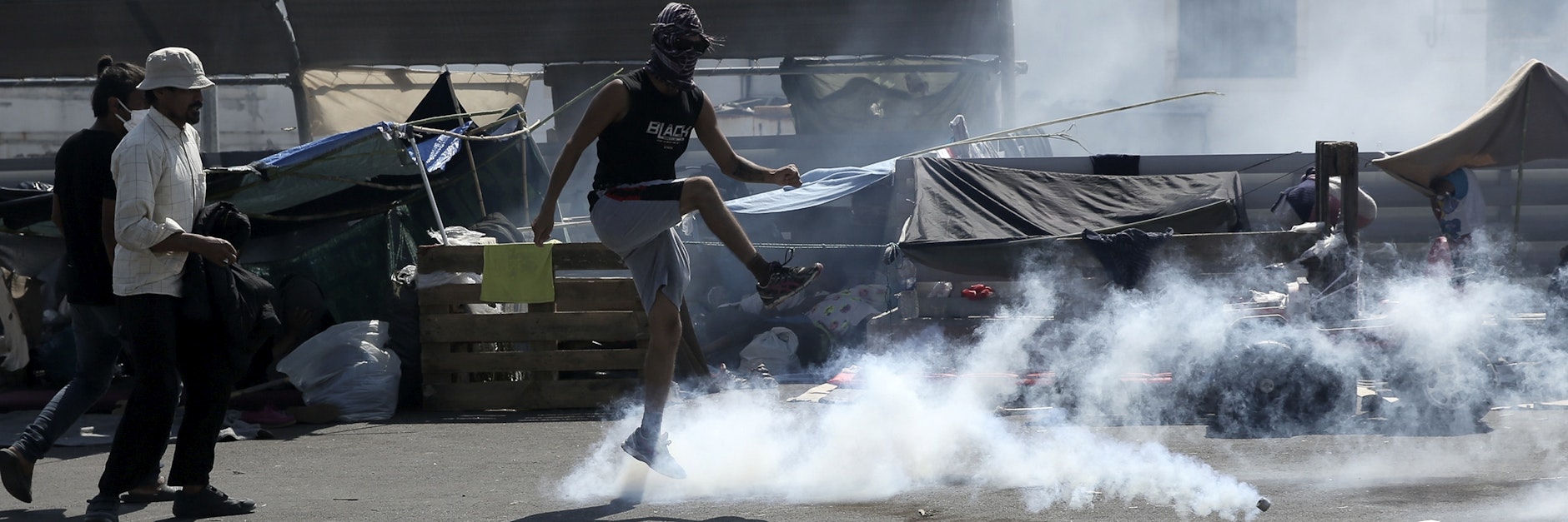 Eine Mann tritt bei Zusammenstößen zwischen Migranten und der Polizei gegen einen Tränengaskanister.