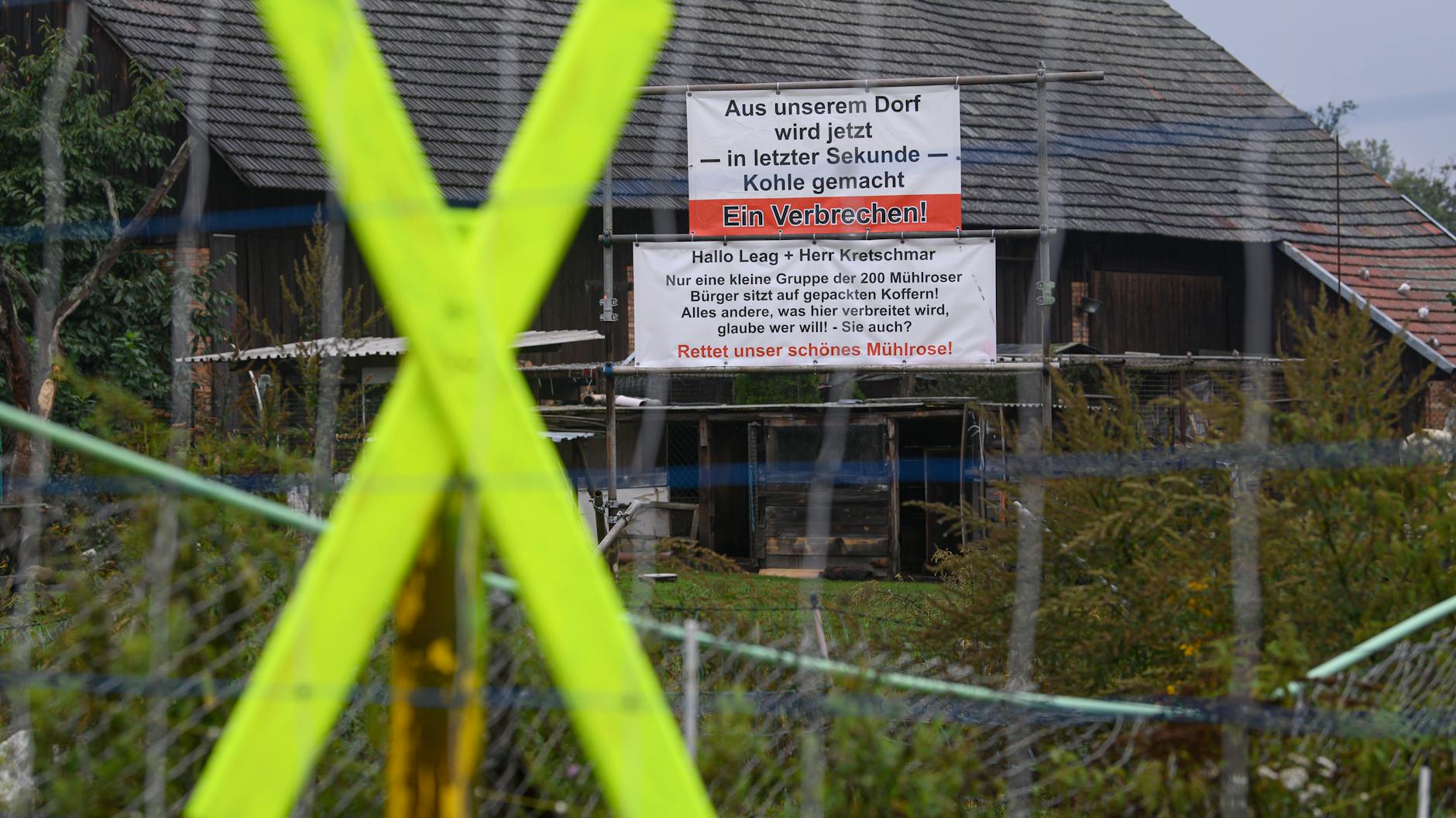 Ein gelbes X und ein Banner zum Protest gegen Umsiedlung und Abriss hängt an einem Haus.