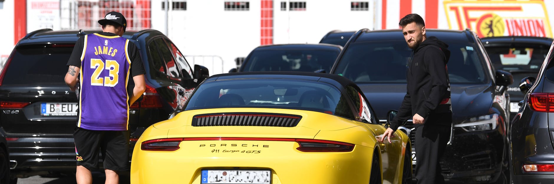 Max Kruse im L.A.-Lakers-Shirt von Superstar LeBron James und Berkan Taz (r.) steigen in einen sündhaft teueren Sportwagen aus Zuffenhausener Produktion.