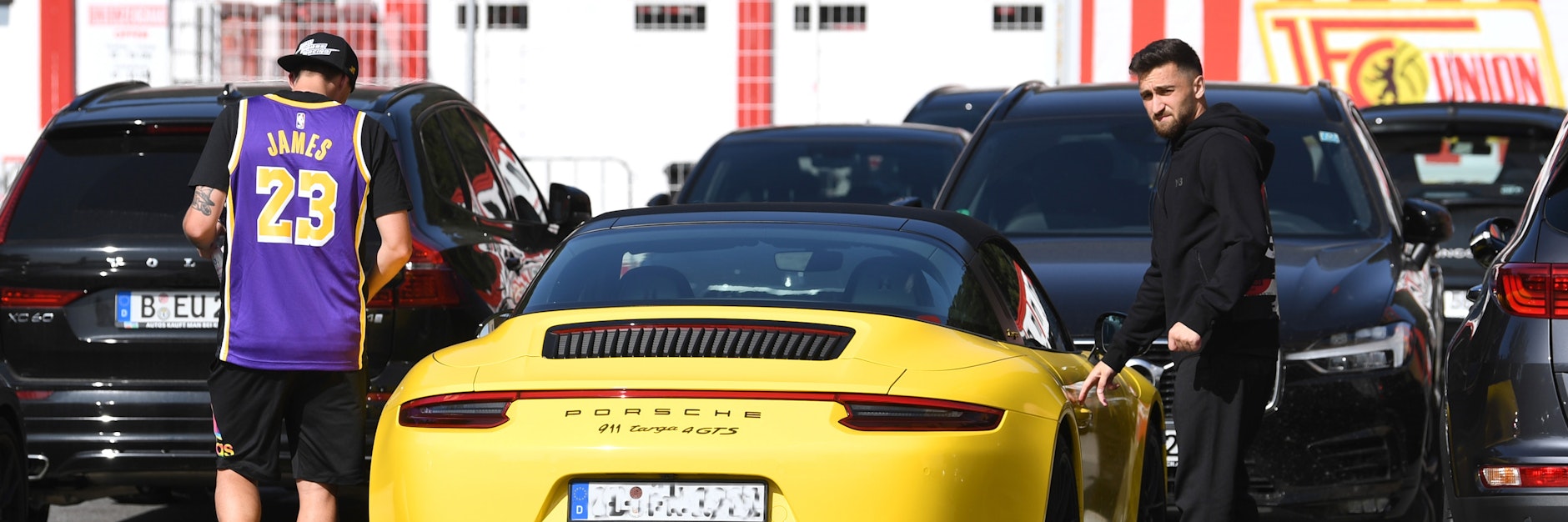 Max Kruse im L.A.-Lakers-Shirt von Superstar LeBron James und Berkan Taz (r.) steigen in einen sündhaft teueren Sportwagen aus Zuffenhausener Produktion.
