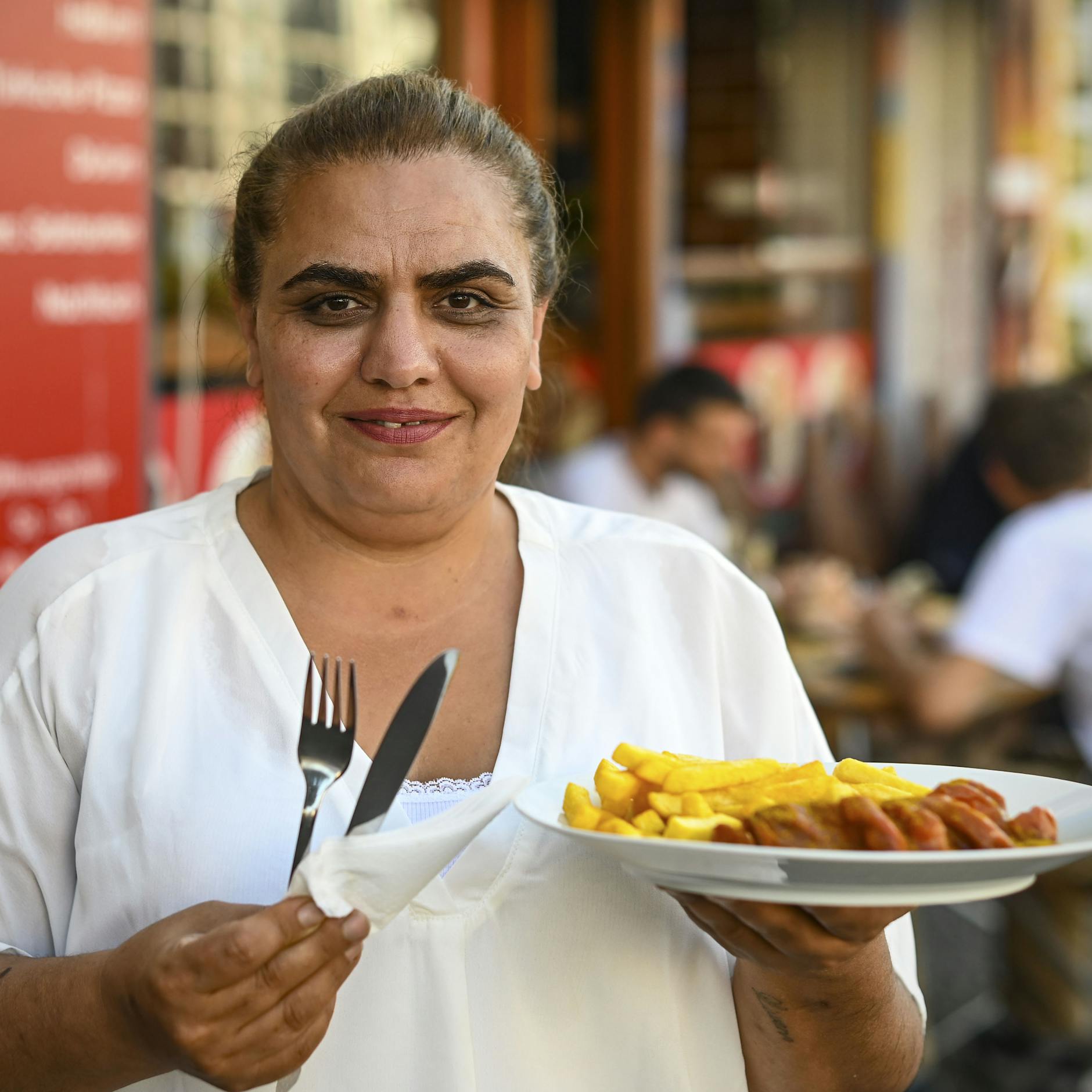 Dilber Dogan serviert Currywurst und Pommes. 