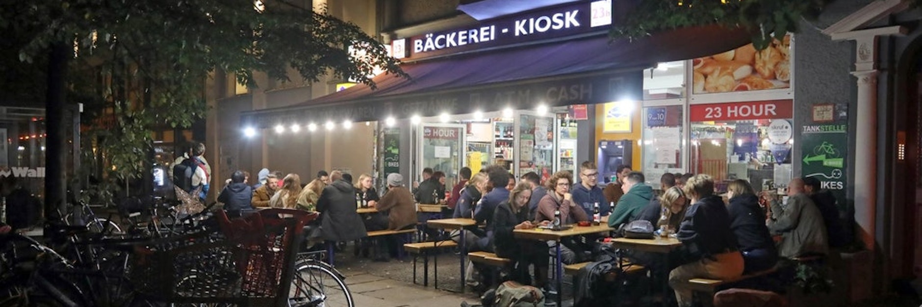 Menschen sitzen nachts vor einem Berliner Späti. Das soll im Bezirk Mitte künftig nicht mehr möglich sein, so das Verwaltungsgericht.