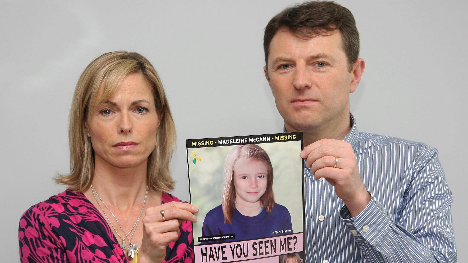Die Eltern der vermissten Maddie McCann mit einem Suchplakat. Darauf ist ein computergeneriertes Bild zu sehen, das zeigt, wie Maddie heute aussehen könnte.