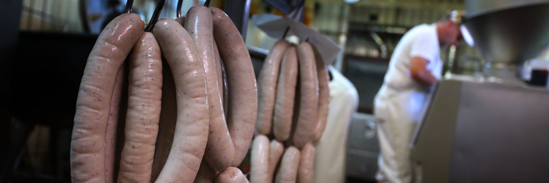 Hinter frisch produzierten Bratwürsten arbeitet Metzger Matthias Freund in seiner Metzgerei.