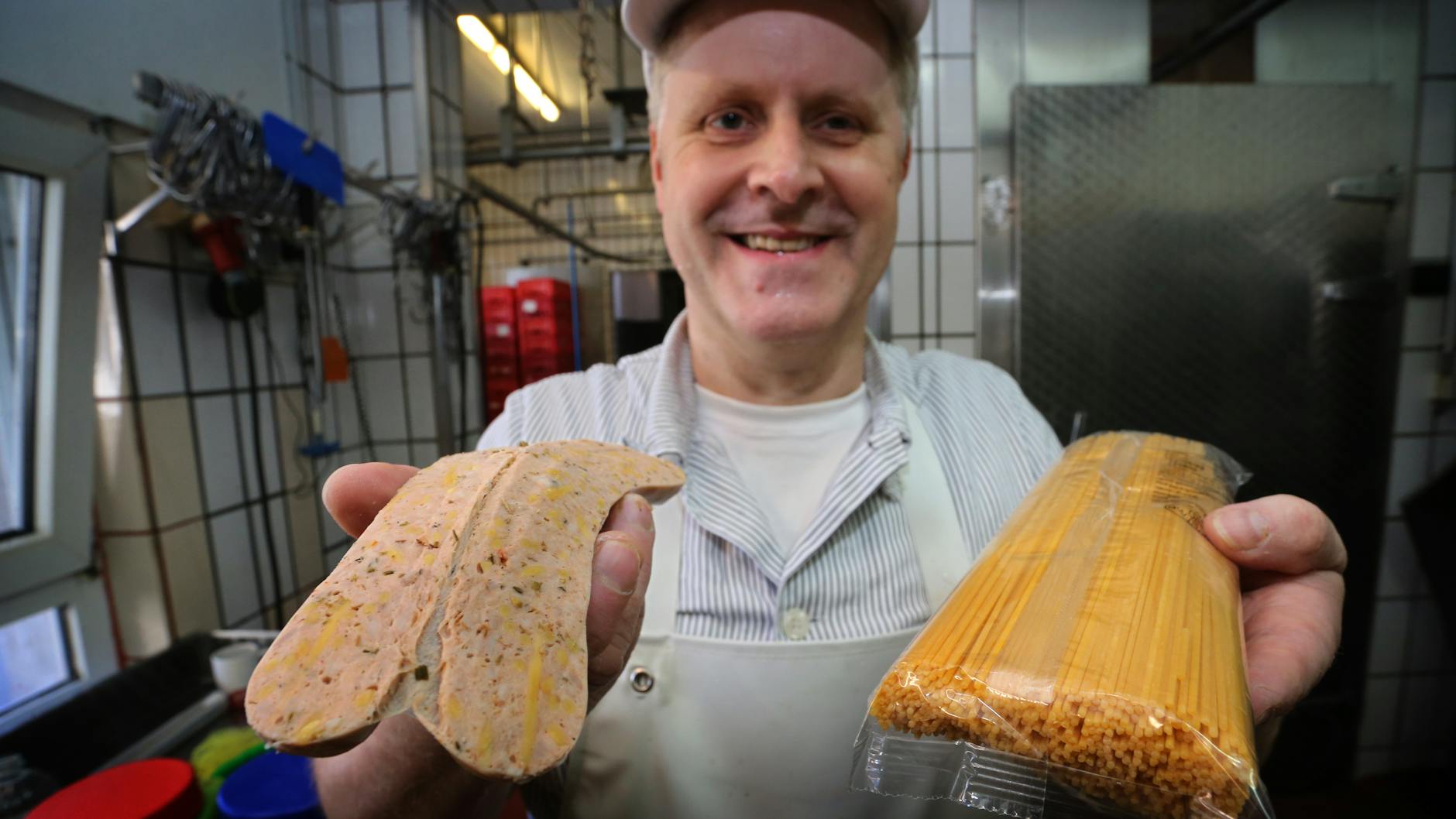 Matthias Freund zeigt in seiner Metzgerei eine Spaghetti-Bolognese-Bratwurst in der Spaghetti zu sehen sind.
