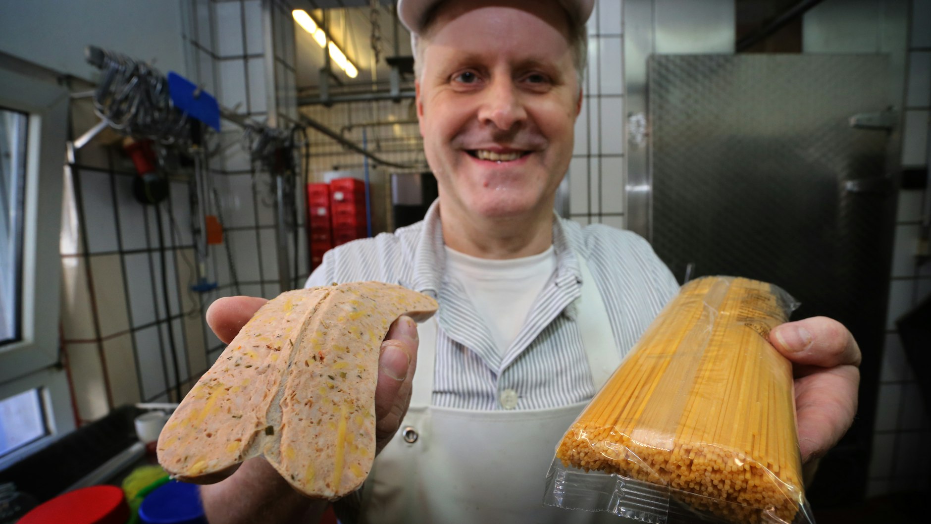 Matthias Freund zeigt in seiner Metzgerei eine Spaghetti-Bolognese-Bratwurst in der Spaghetti zu sehen sind.