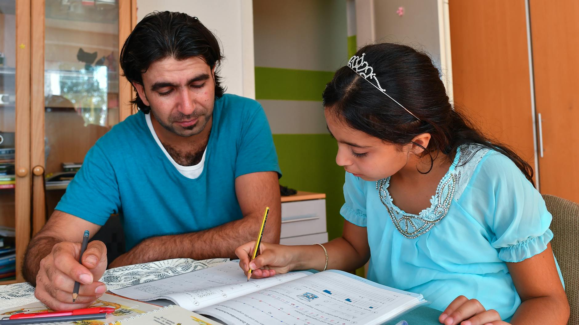 Das syrische Mädchen Nour und ihr Vater Mahmoud beim den Hausaufgaben für die Schule