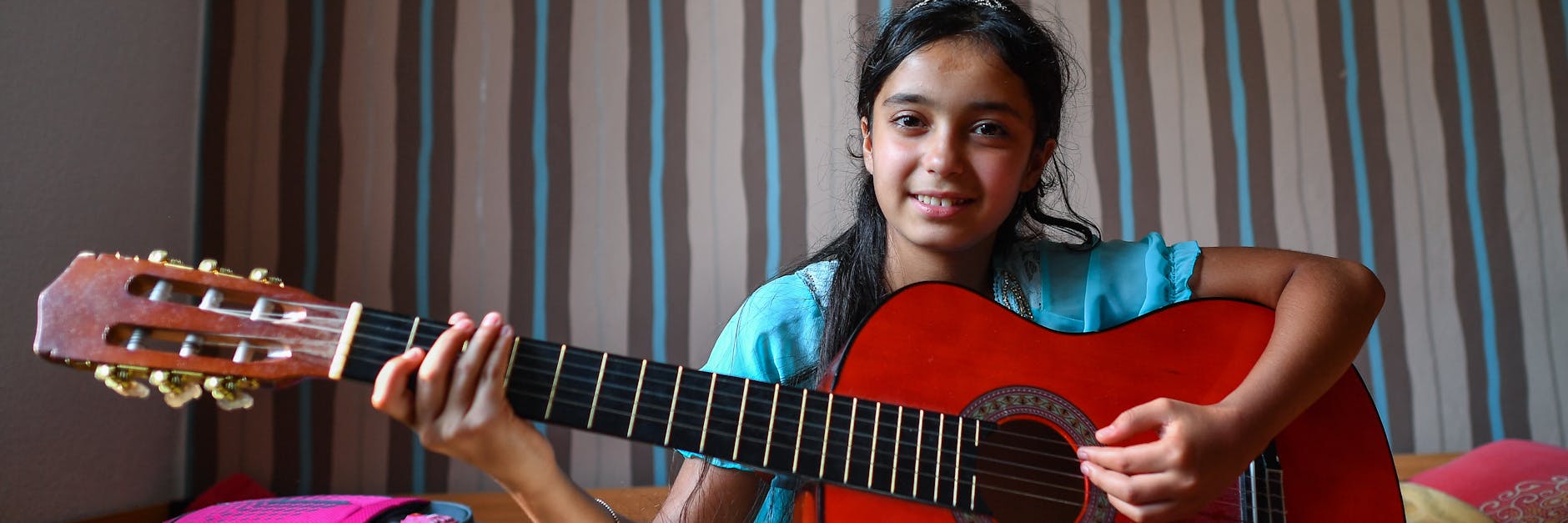 Das syrische Mädchen Nour sitzt in ihrem Zimmer im Oderbruchort Golzow (Brandenburg) und spielt Gitarre. 