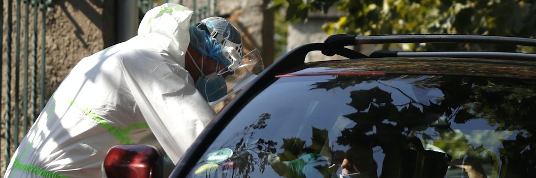 Ein medizinischer Mitarbeiter untersucht einen Autofahrer an einer Drive-in-Teststation in Prag.