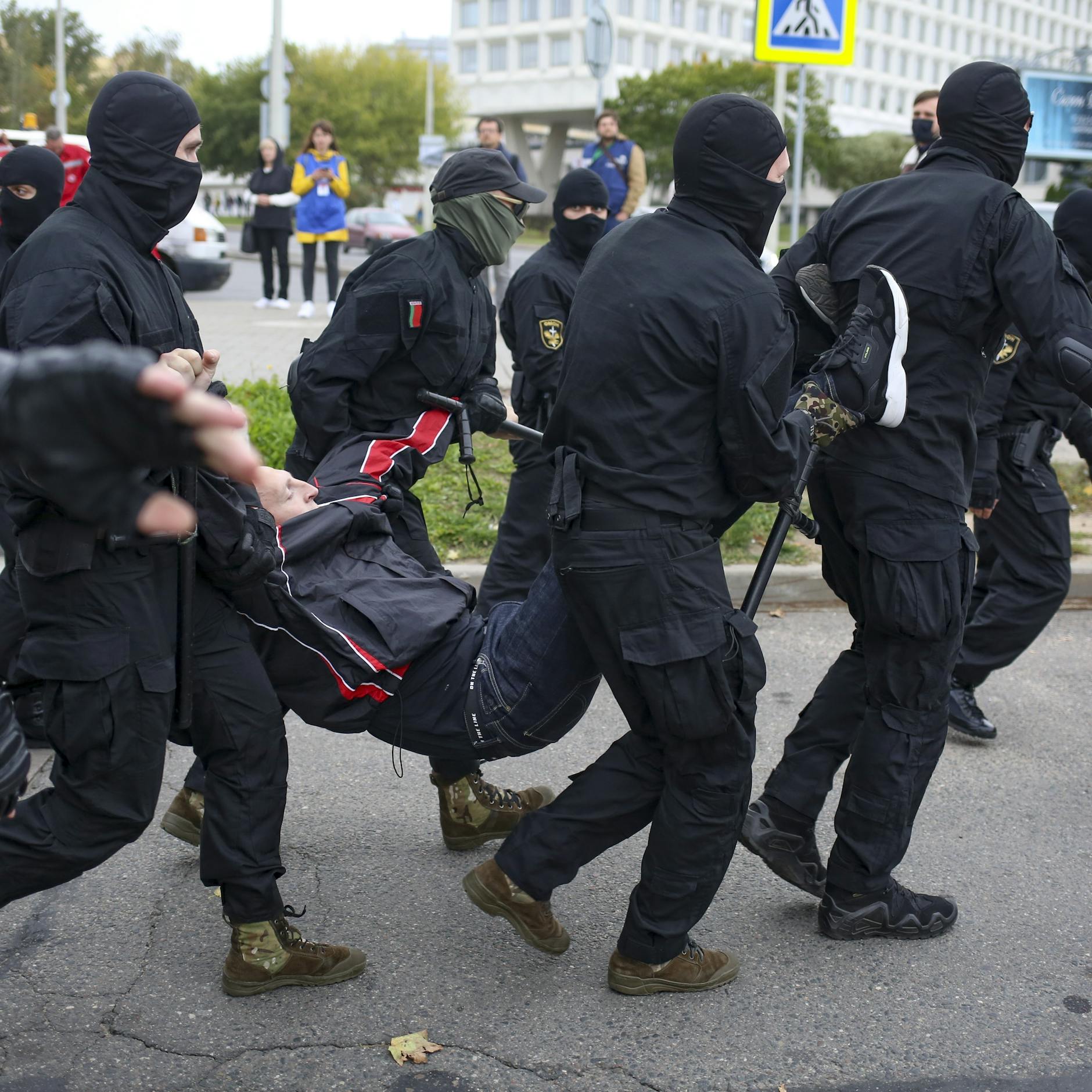 Die Polizisten sind vermummt, tragen einen Demonstranten weg.