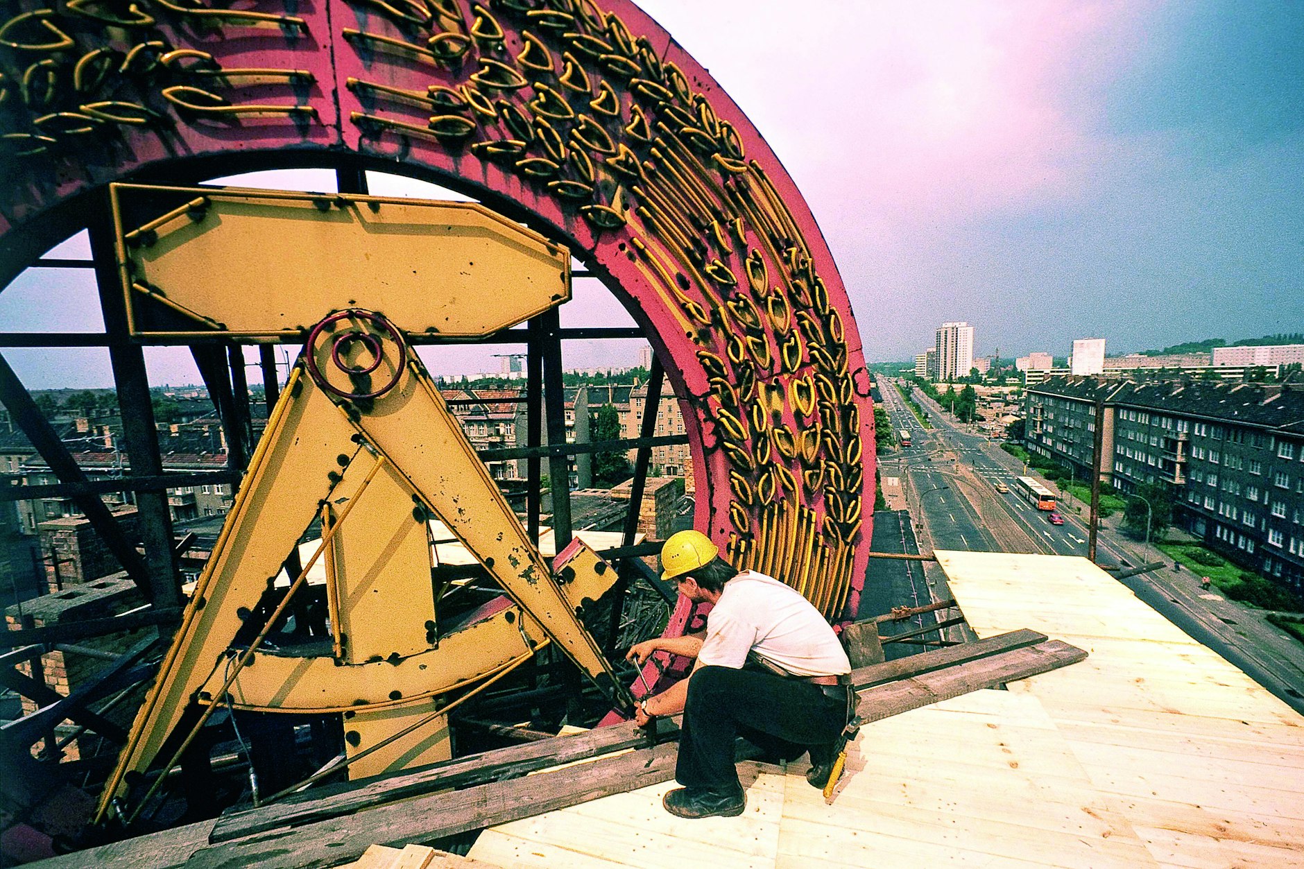 Am Ende. Ein Arbeiter auf einem Hochhaus in Ost-Berlin beginnt mit dem Abbau des Staatswappens der DDR. Die Volkskammer hat am 31. Mai 1990 beschlossen, das Emblem von allen öffentlichen Gebäuden zu entfernen. Der Abriss der Berliner Mauer beginnt zwei Wochen später.