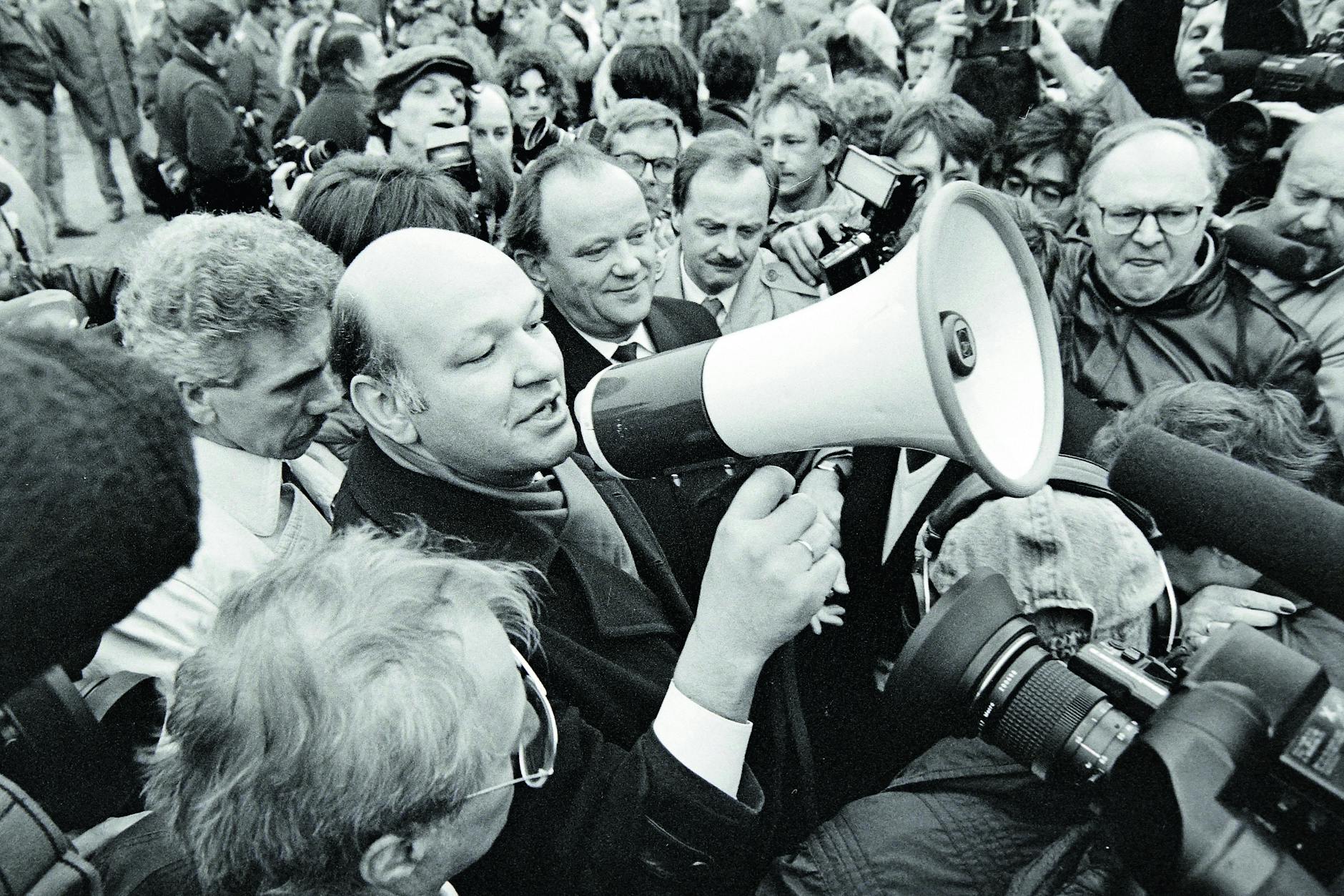 Aufbruchstimmung. Walter Momper, Regierender Bürgermeister von West-Berlin, hält am 12. November 1989 auf dem Potsdamer Platz eine Rede. Anlass ist die Öffnung eines neuen Grenzübergangs. Der Mann links neben ihm Erhard Krack, Oberbürgermeister von Ost-Berlin.
