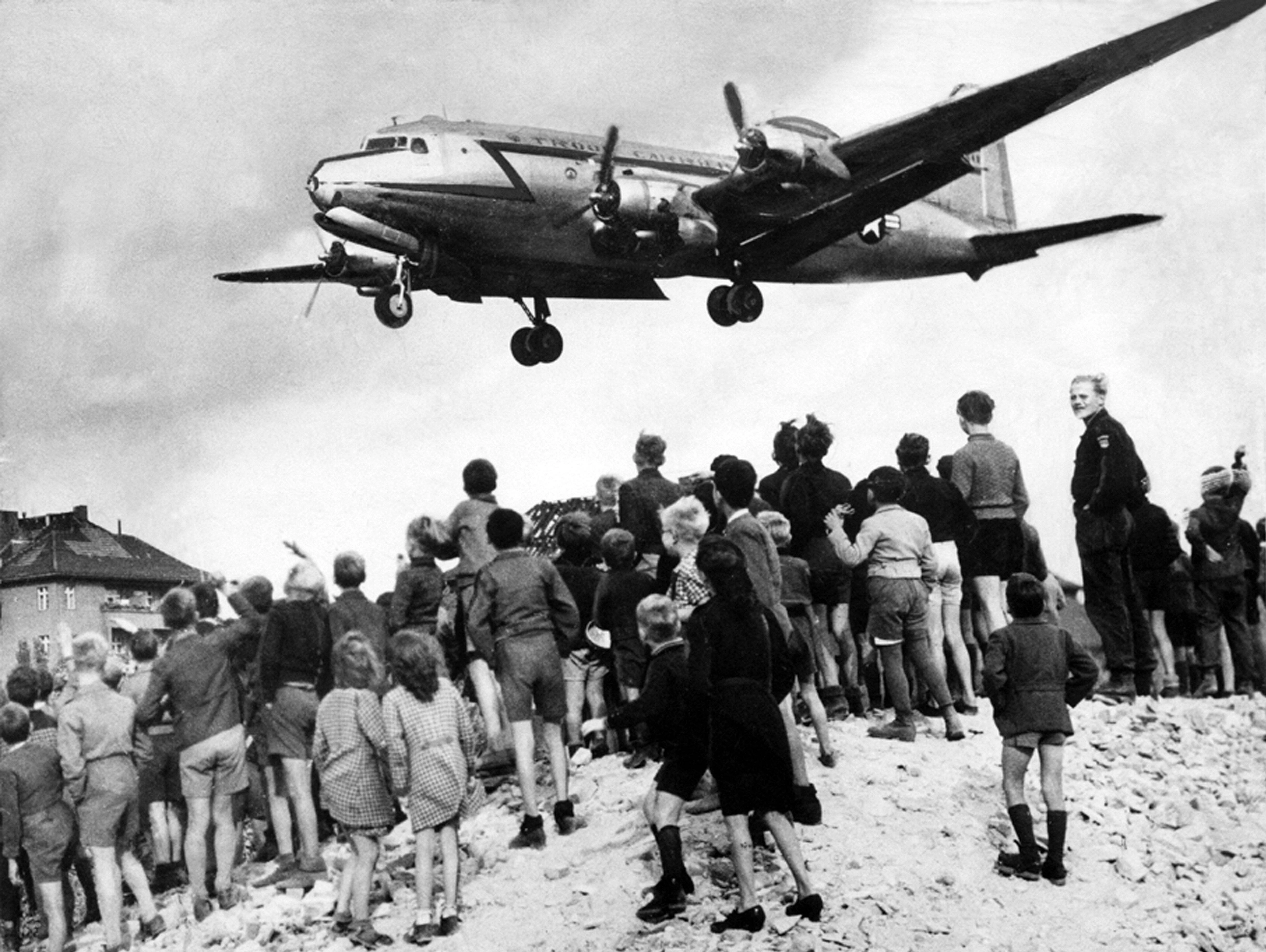 Berlin-Blockade 1948/49: West-Berliner beobachten ein Transportflugzeug (Rosinenbomber) der US Air Force im Landesanflug auf den Flughafen Tempelhof.