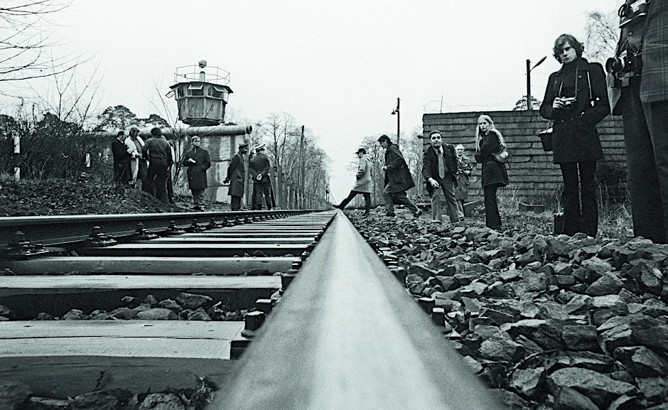 Tensions subside in Steinstücken: An exchange of territory is negotiated in the 1971 Four Power Agreement. A corridor connects the exclave with West Berlin. Residents and journalists wait at the train tracks for a visit by politicians and the US military.