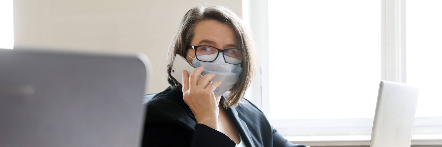 Eine Frau trägt Maske bei der Büroarbeit.