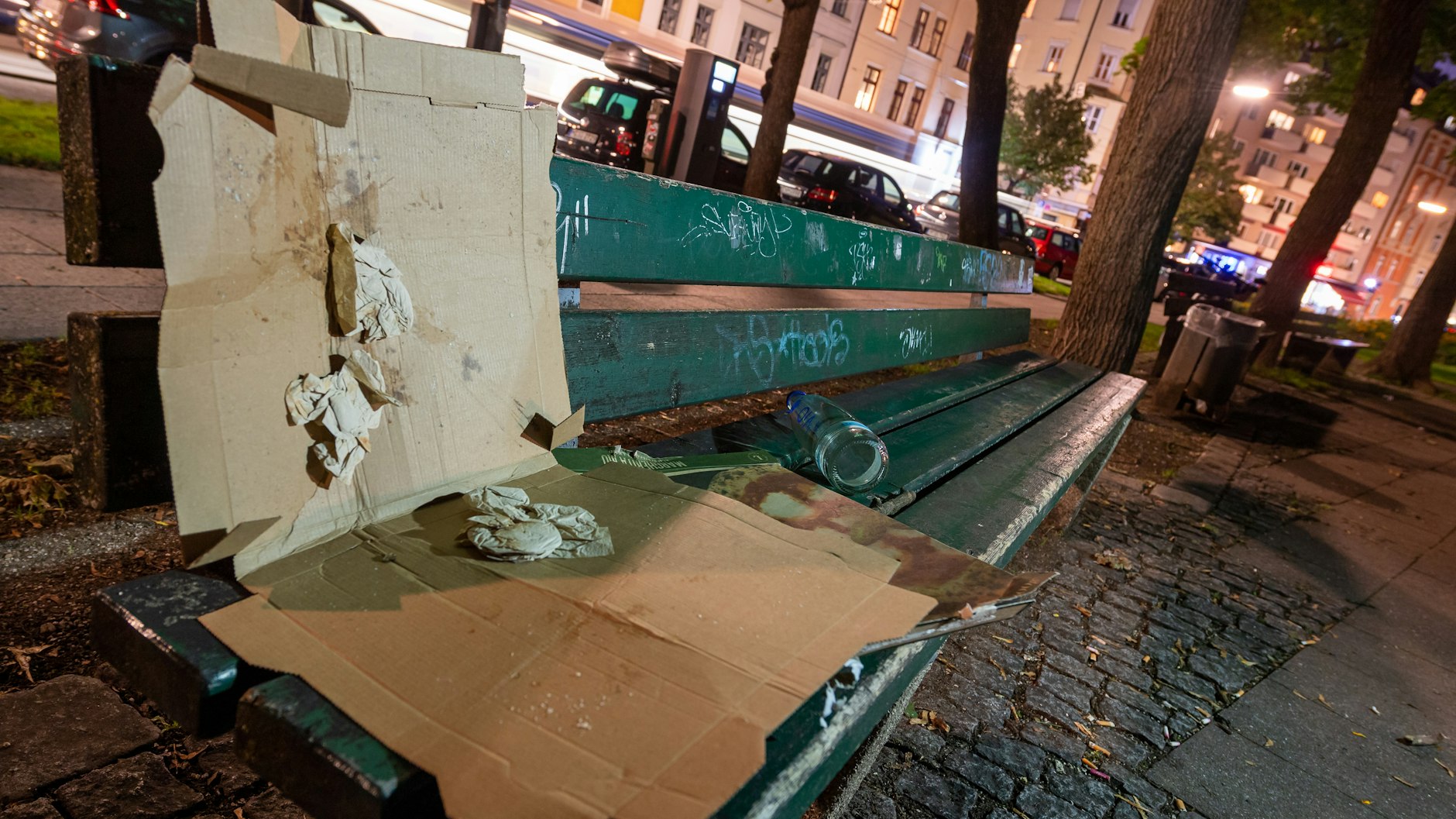 Ein leerer Pizzakarton liegt auf einer Parkbank in München.