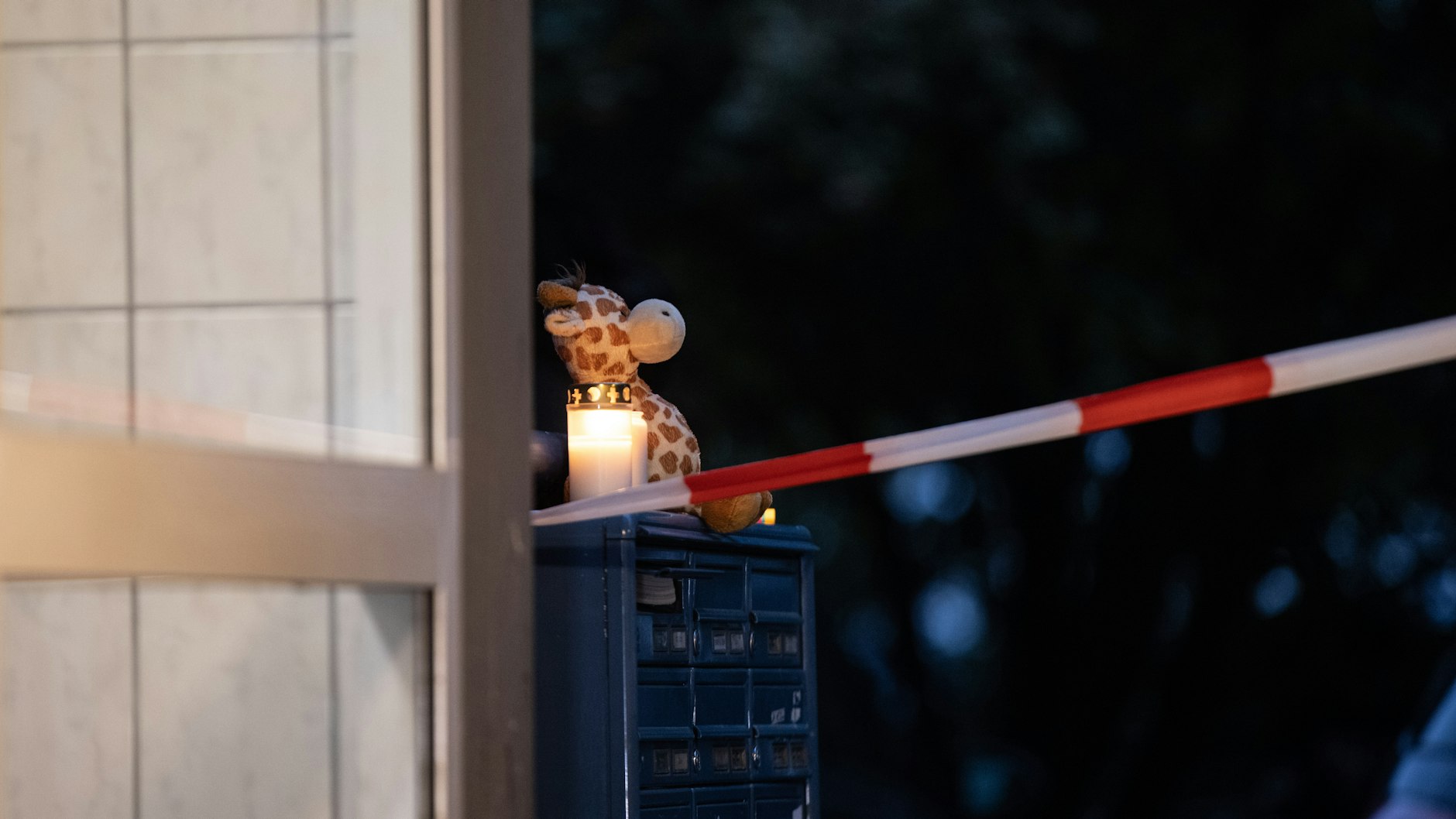 Eine Plüschgiraffe steht neben Kerzen auf einem Briefkasten vor dem Wohnhaus. Eine 27-jährige Mutter soll in Solingen fünf Kinder umgebracht haben.
