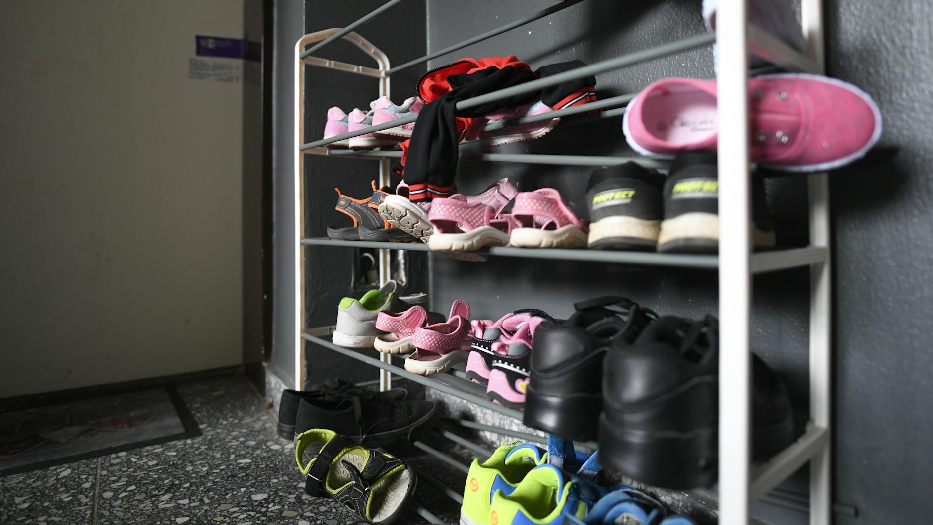 Kinderschuhe liegen in einem Schuhregal vor der Tür der Wohnung, in der die fünf Kinder starben.