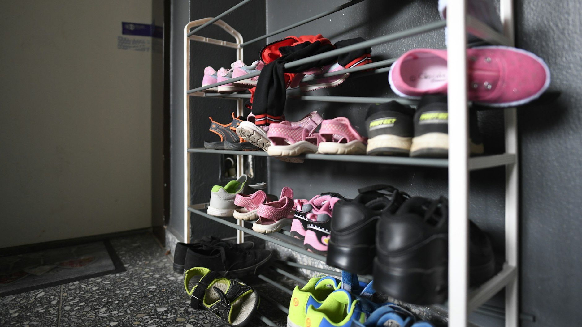 Kinderschuhe liegen in einem Schuhregal vor der Tür der Wohnung, in der die fünf Kinder starben.