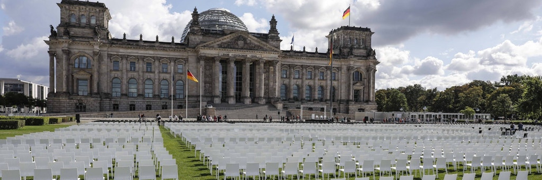 Wie ein stummes Publikum, die Augen auf das Parlament gerichtet, stehen die weißen und schwarzen Stühle da.