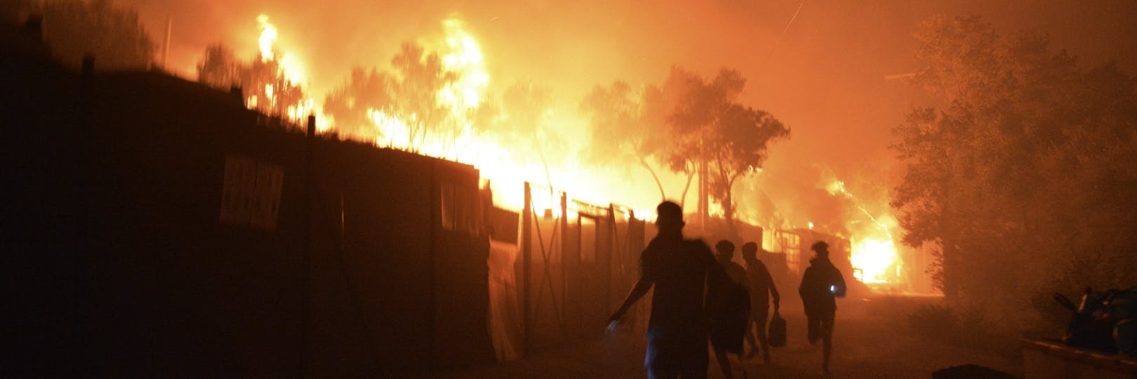 Geflüchtete rennen während ein Feuer im Flüchtlingslager Moria auf der Insel Lesbos brennt. Medienberichten zufolge stehen auch Wohncontainer in Flammen, weshalb die Behörden das Lager evakuierten. 