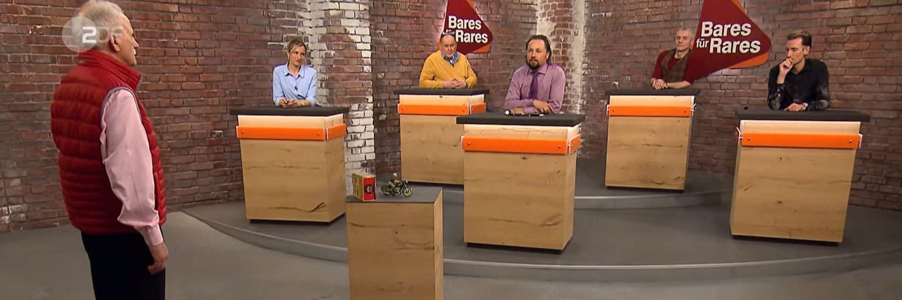 Ingo Wasel im Händlerraum von „Bares für Rares“. Er preist sein Spielzeug-Motorrad an.