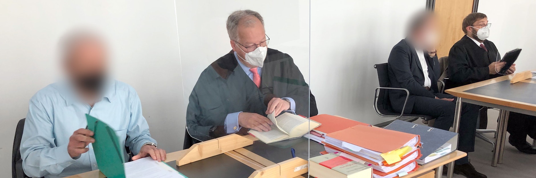 Die Angeklagten (erster v. l. sowie dritter v. l.) sitzen mit ihren Verteidigern vor dem Start der Verhandlung im Gerichtssaal des Amtsgerichts.