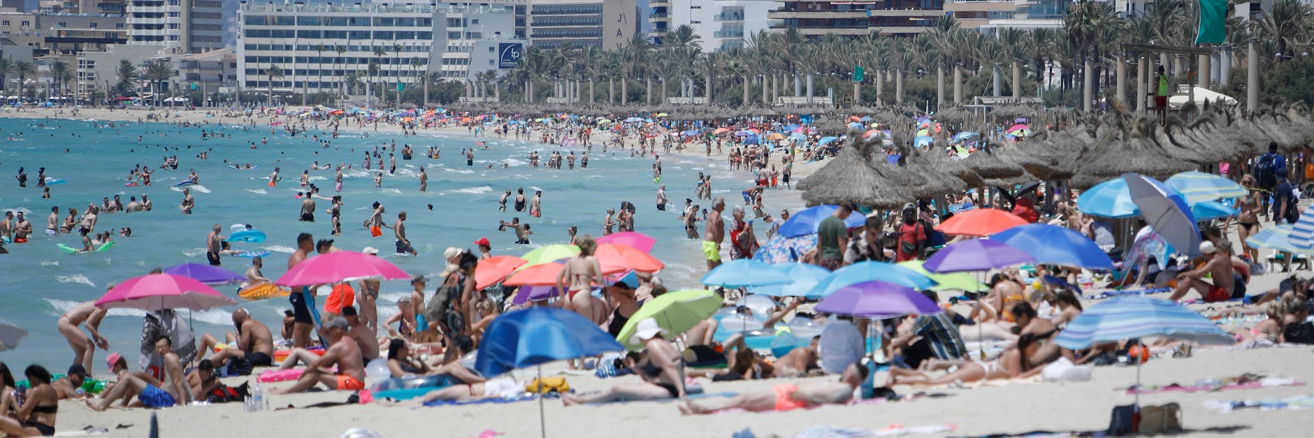 Touristen genießen die Sonne am Strand von Arenal.