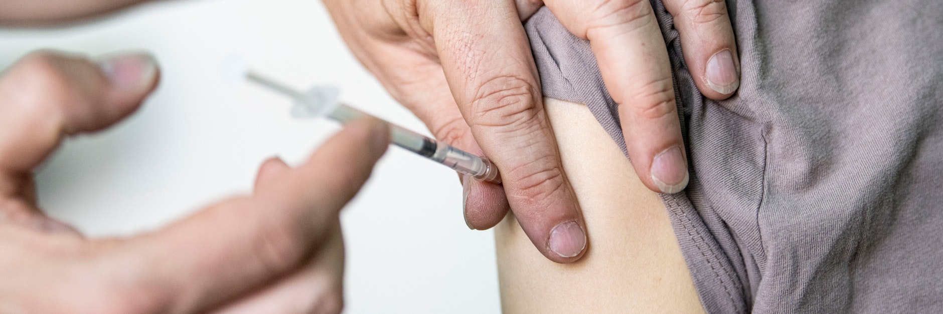 Ein Arzt verabreicht einer jungen Frau eine Corona-Impfung.