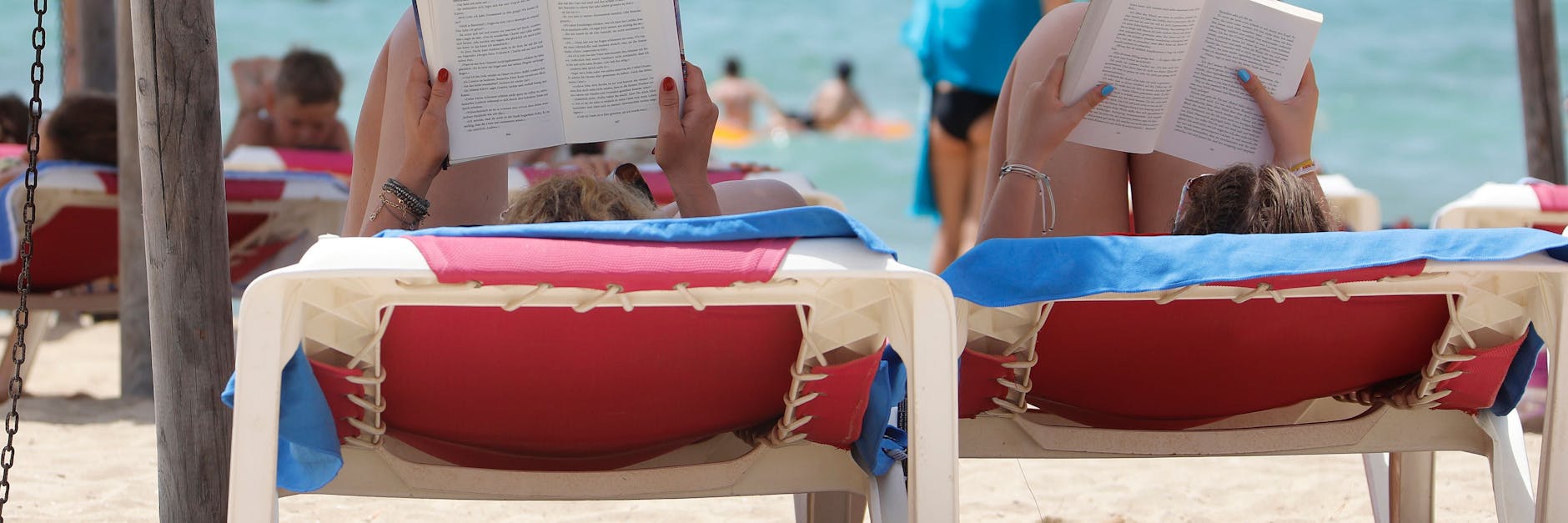 Zwei Frauen liegen am Strand El Arenal auf Mallorca auf Liegestühlen.