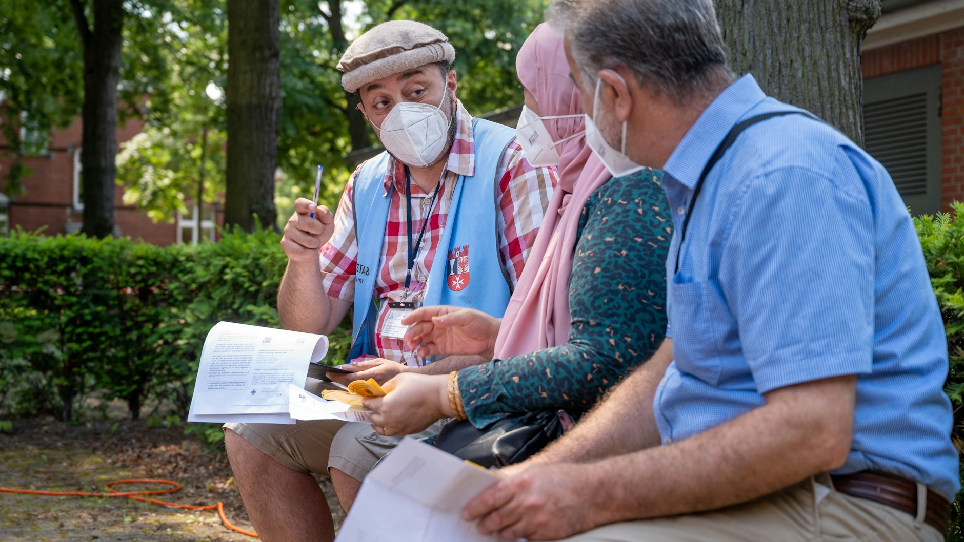 Taman Noor (l), Leiter des Interkulturellen Aufklärungsteams für Berlin Neukölln (IKAT), berät bei einer Impfstelle auf dem Gelände des Bezirksamts Neukölln Menschen zum Thema Corona-Schutzimpfung. Noor leitet ein siebenköpfiges Team, das in rund zehn Sprachen an öffentlichen Orten und Migranten-Treffs zum Thema Corona berät.