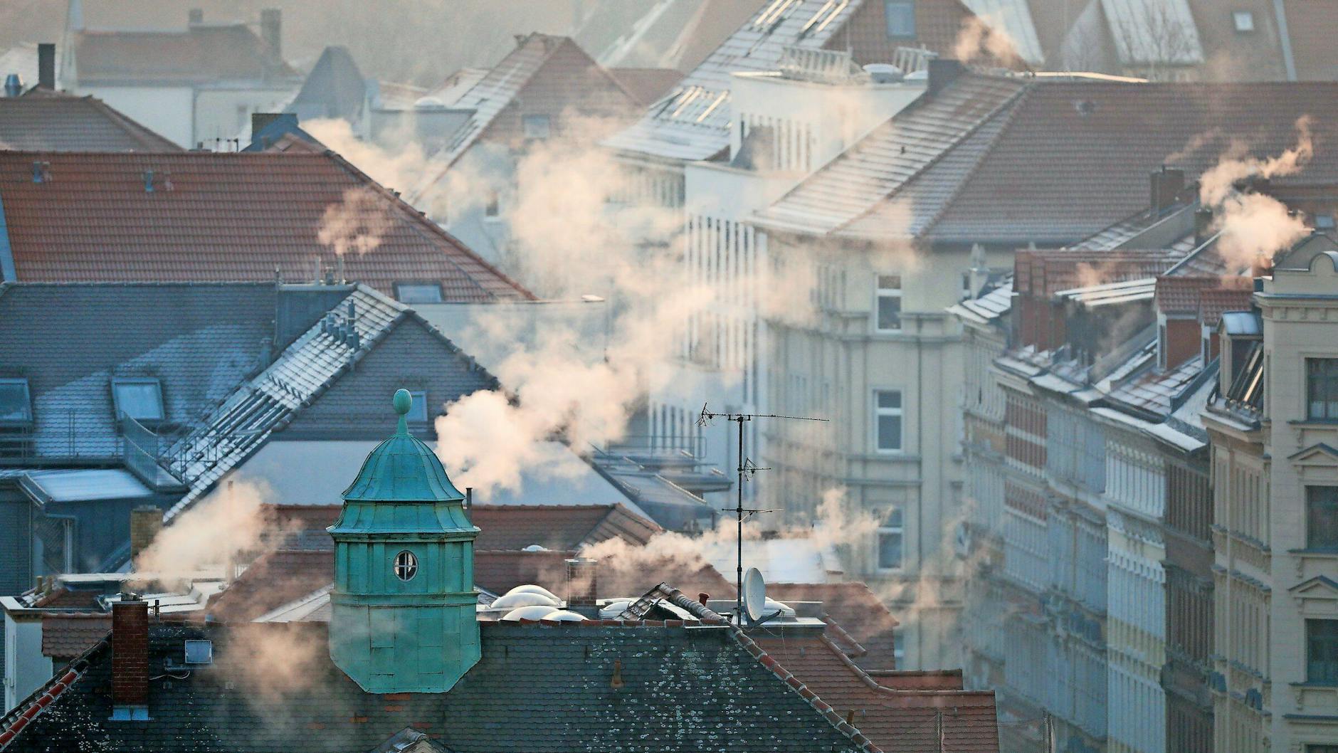 Rauch steigt in einem Wohngebiet aus den Schornsteinen. In Zukunft sollen Kachelöfen und Kamine Schornsteine erhalten, die weit über das Dach hinausragen.