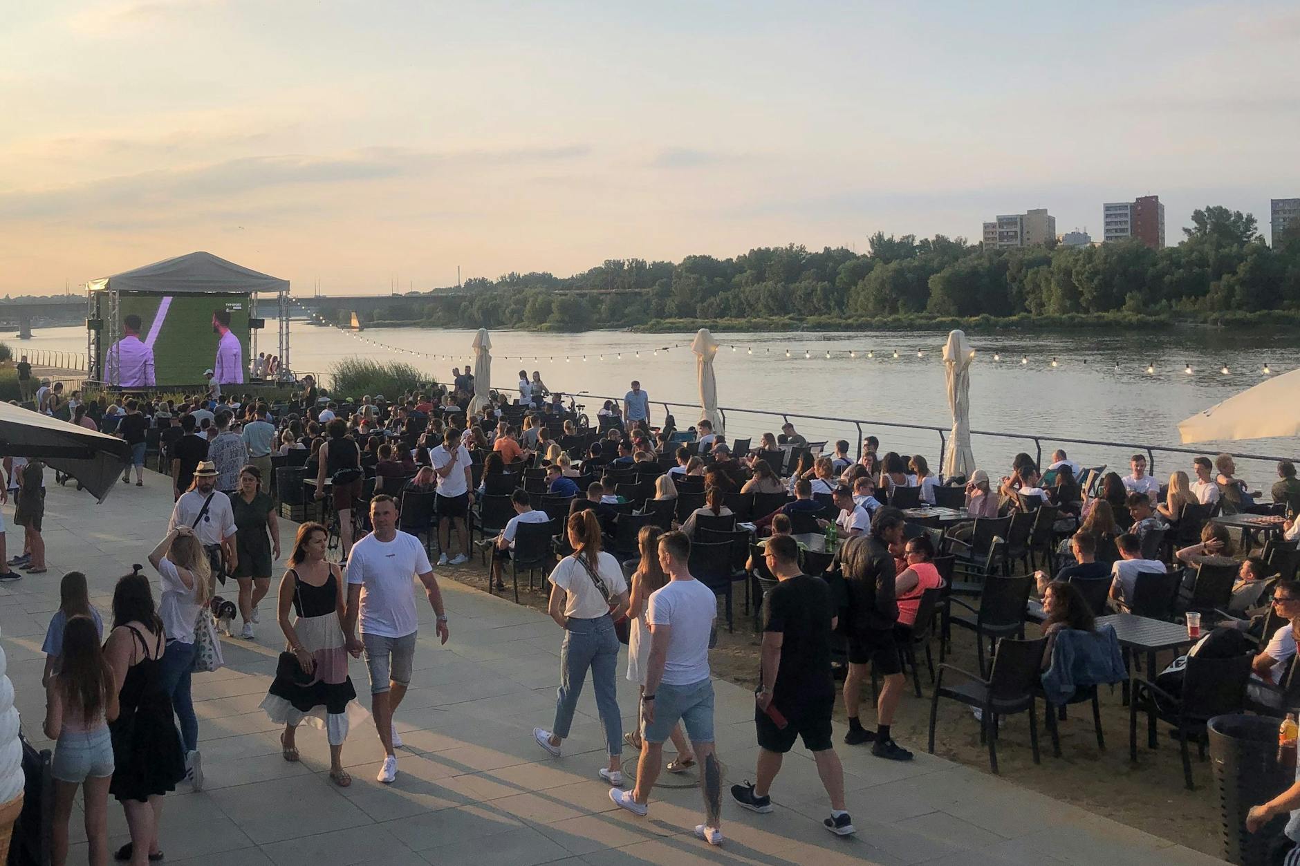 Menschen beim Flanieren an der Weichsel, andere sehen sich gemeinsam das EM-Finale an.