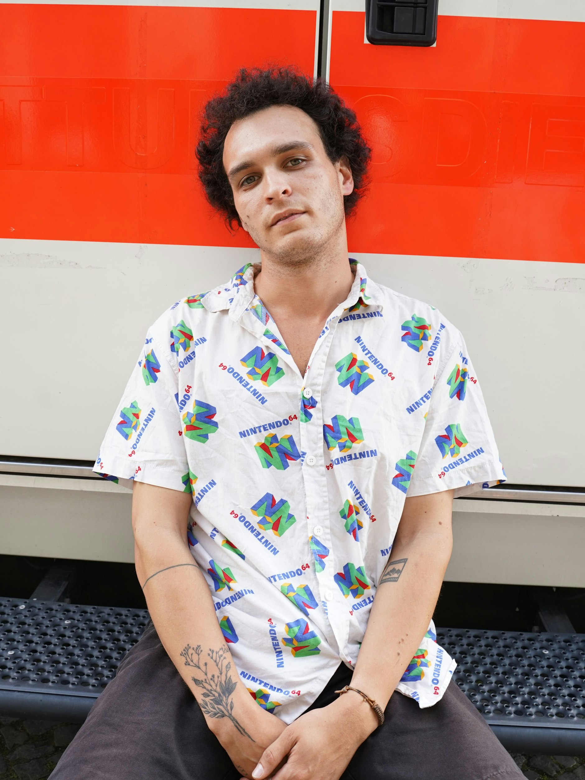 Kameramann Luc dreht  vor allem Werbung. Als er vor einigen Jahren für einen Job nach Oregon flog, ging sein Gepäck verloren und er musste  sich vor Ort  günstige Ersatzkleidung kaufen.  Bei TK Maxx fand er dieses Nintendo-Hemd für ganze 6 Dollar. Das florale  Tattoo ist ganz frisch,  es symbolisiert die  Trockenblumen, mit denen das Paar die gemeinsame  Wohnung ausstaffiert hat. Luc lernte seine Freundin&nbsp; auf dem Pausenhof kennen. Sehr romantisch!