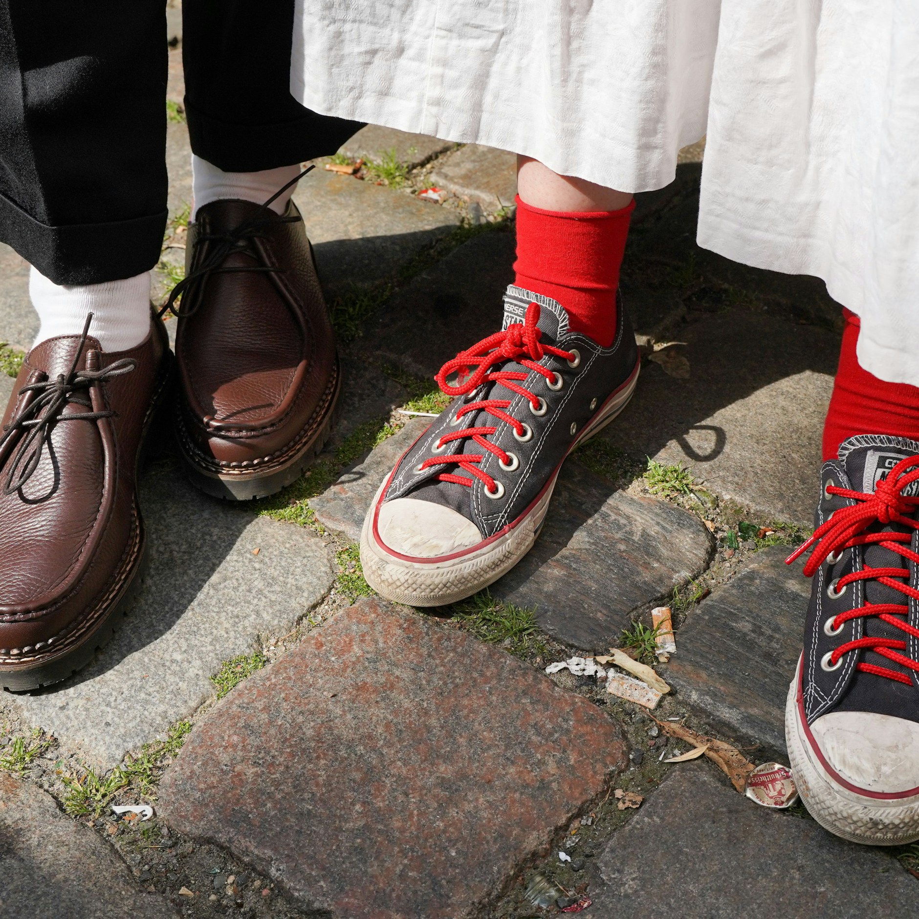 Paar und Schuhe: Lederschuhe von Mango und Chucks mit roten Socken.