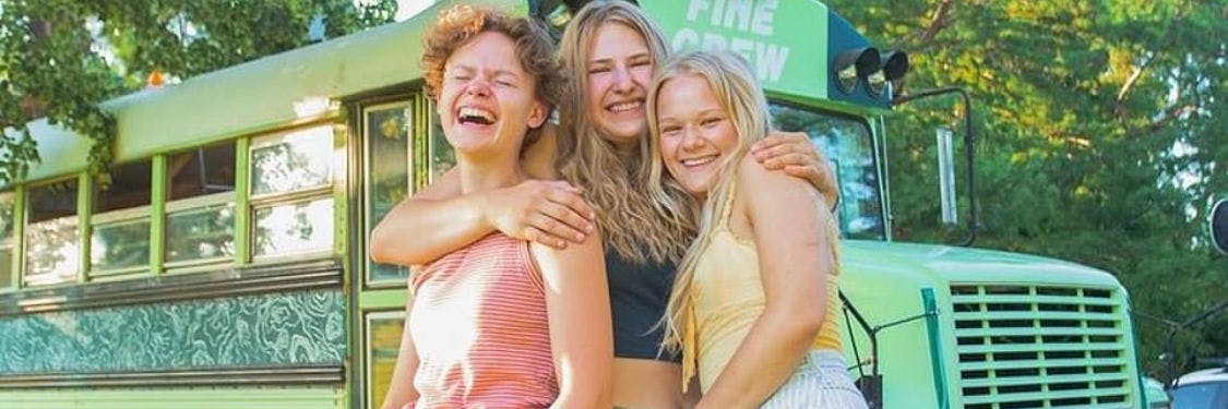 Bekah King, Abi Roberts und Morgan Tabor stehen zusammen vor ihrem umgebauten Schulbus.