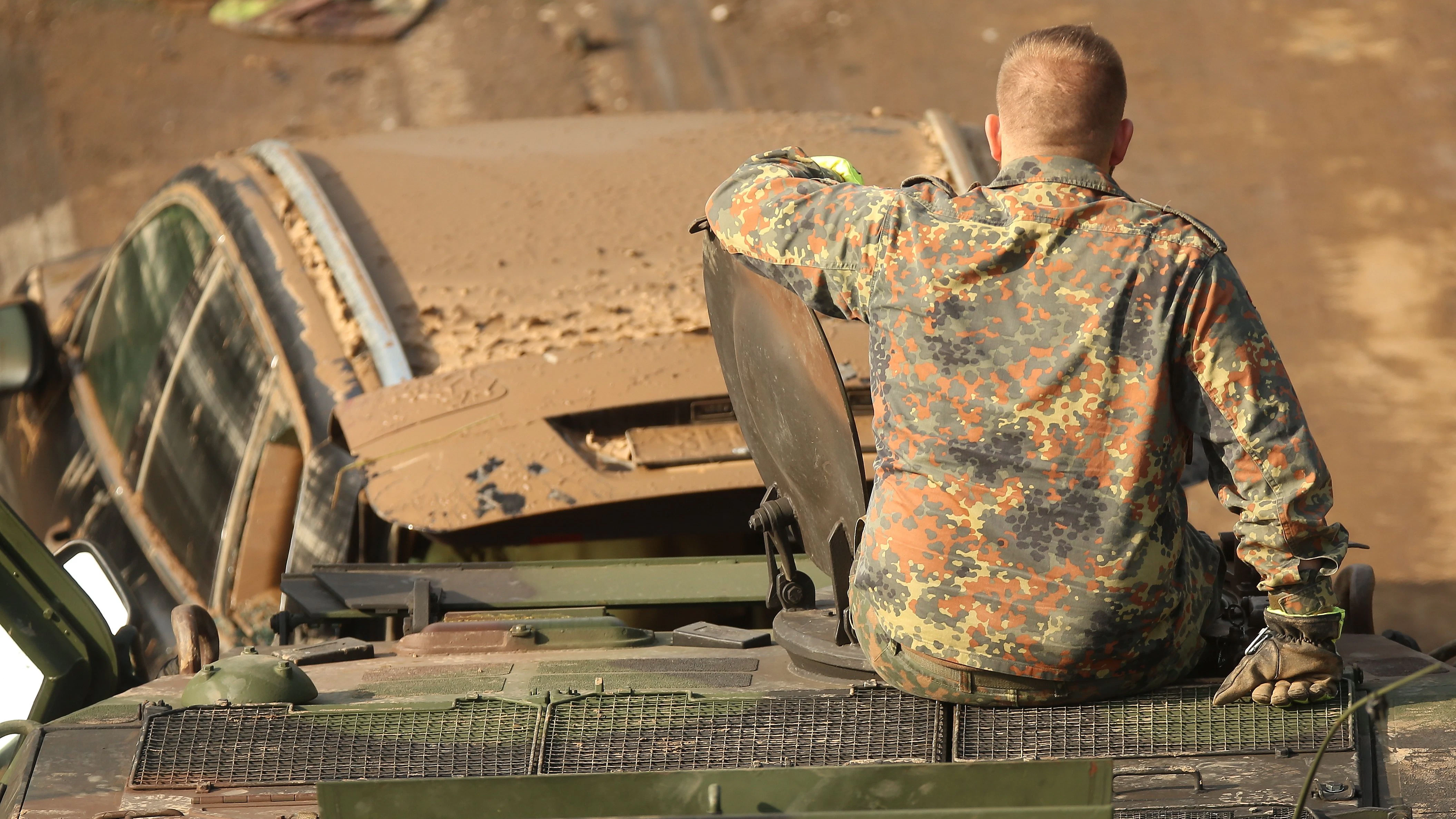 Ein Panzer der Bundeswehr schleppt ein zerstörtes Auto ab. 