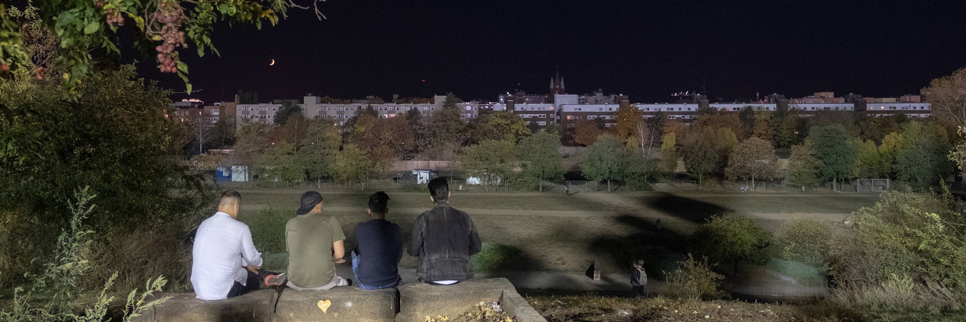 Menschen sitzen in der Nacht im Mauerpark.