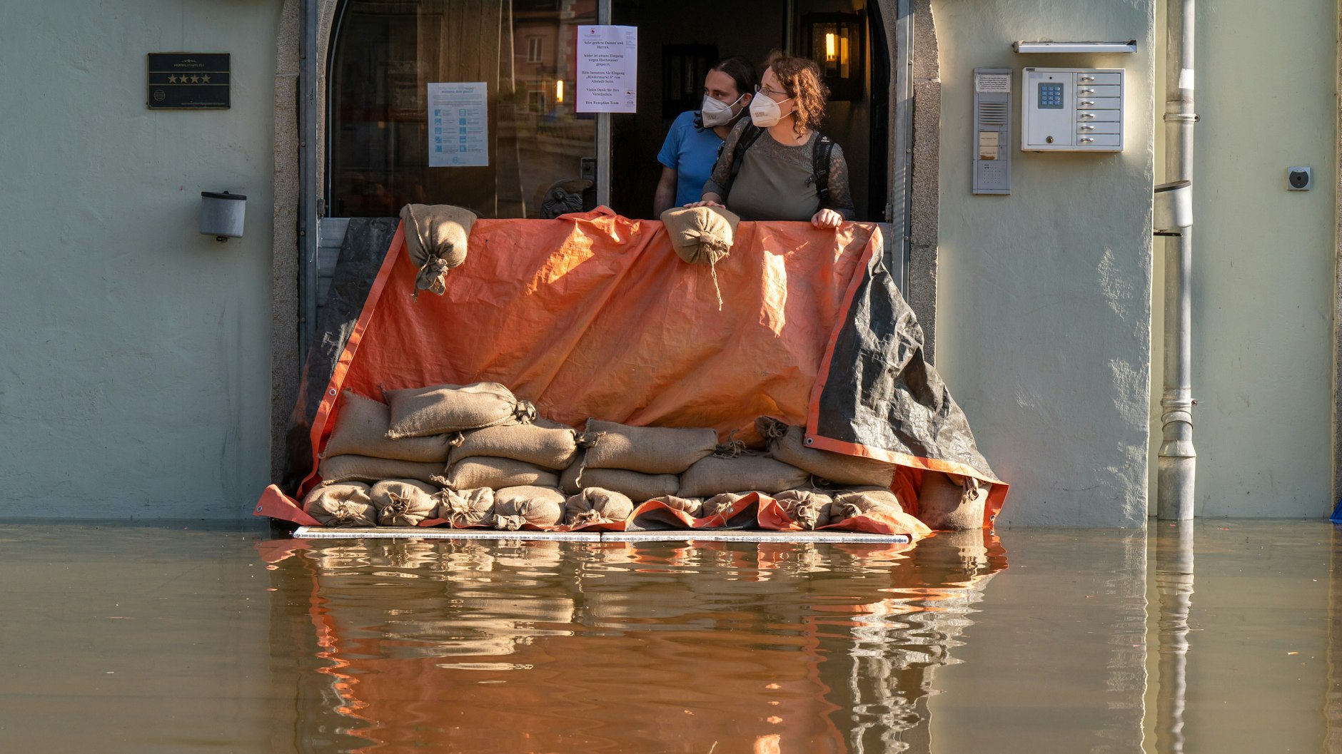 Zwei Frauen schauen aus dem Eingang eines Hotels im bayerischen Passau über die Hochwassersperre, die das Gebäude vor dem Wasser der Donau schützen soll.
