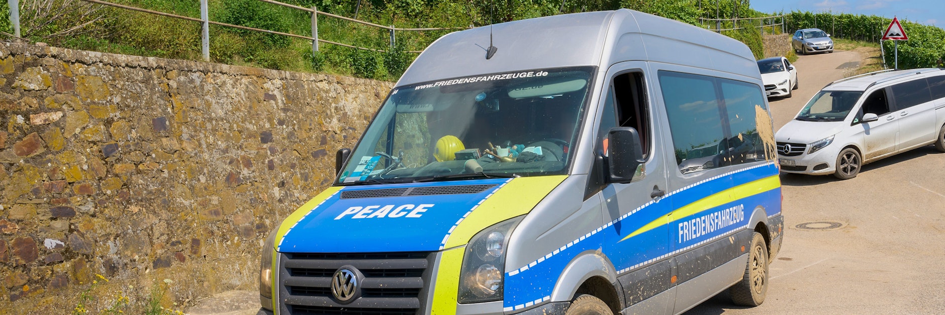 Querdenker im Hochwasser-Gebiet: Ein Transporter im Polizei-Look mit der Aufschrift "Friedensfahrzeug" fährt am Rand des Katastrophengebiets in den Weinbergen entlang.