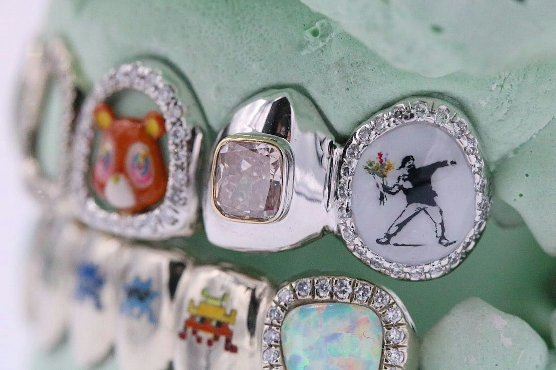 Ein aktuelles Werk des New Yorker Promi-Juweliers Gabby Elan: Grillz mit Kunst von Banksy („The Flower Thrower“) und  Takashi Murakami x Kanye West („Graduation Bear“).